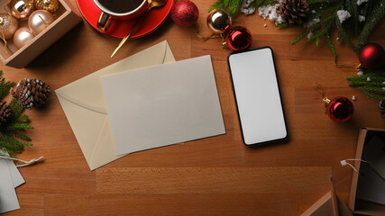 Wooden table with smartphone, card, envelope and decorations in Christmas concept