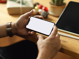 Cropped shot of male hands using horizontal smartphone on wooden table