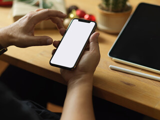 Cropped shot of male hands using smartphone on wooden table