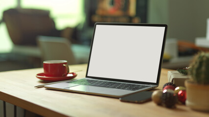 Mock up laptop on wooden table with smartphone, cup and decorations in office room