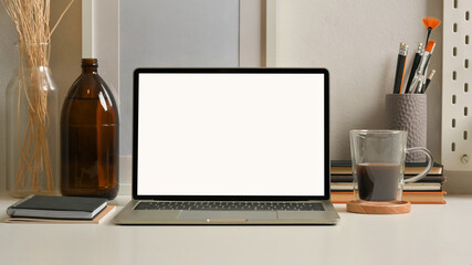 Mock up laptop on white table with stationery, supplies and decorations in home office