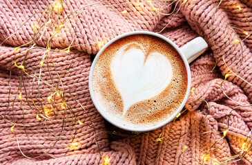Coffee with a heart pattern on a warm knitted sweater