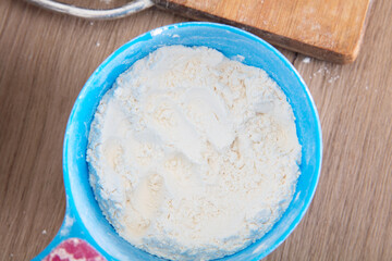 Looking down and shooting a plastic scoop full of white flour on the table