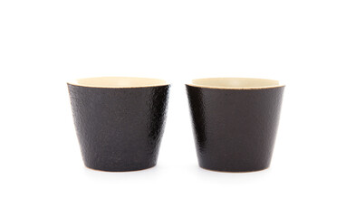 Two black coarse porcelain tea cups on white background