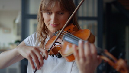Woman learning to play violin at home. Romantic girl playing violin with bow © stockbusters