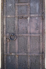 Old metal door with geometric decoration and large ring. Texture of old metal surface with cracks and corrosion