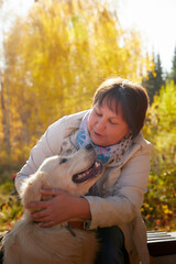 A plump woman with a white Labrador dog walking in a Park or forest on a Sunny autumn day.