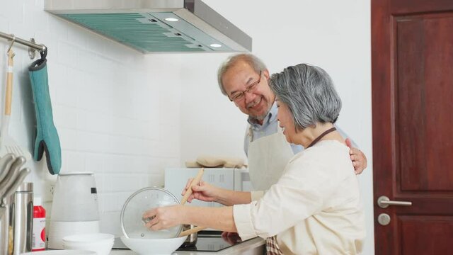 Asian senior woman cooking food and let her husband smelling the soup.