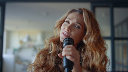Singer practicing vocal with microphone. Attractive woman singing song at camera