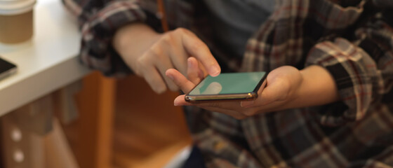 Obraz premium Female in Scott shirt using smartphone while sitting at workplace