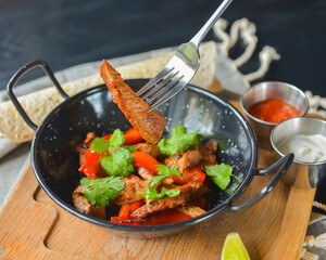 Vegetables and meat in wok pan served with lavash bread and different kinds of sauce. Close up.