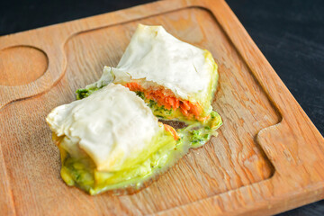 Wrap sandwich with pink salmon and spinach in lavash bread. Delicious snack concept, served on a rustic wooden board.