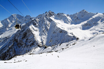 Fototapeta na wymiar Skiers on the Elbrus mountain track and the Krugozor station of the gondola cable car, Elbrus region, Caucasus