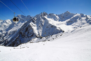 Landscape with skiers on the Elbrus mountain track and a gondola cable car, Elbrus region, Caucasus