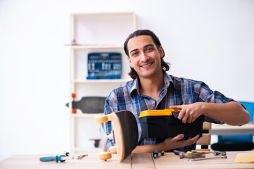 Young man repairing skateboard at workshop