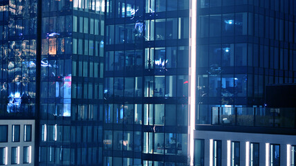 Obraz premium Pattern of office buildings windows illuminated at night. Lighting with Glass architecture facade design with reflection in urban city.