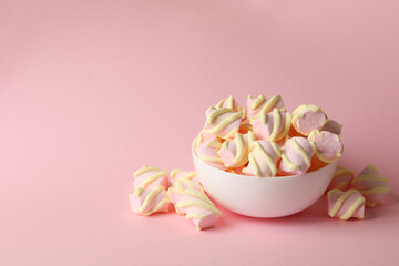 Bowl with marshmallow on pink background, space for text