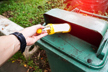 man throws a plastic water bottle into a green trash bin.Environmental protection concept
