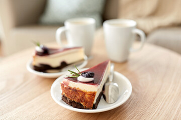 food, junk-food, culinary, baking and holidays concept - piece of delicious cherry chocolate layer cake on saucer with spoon on wooden table