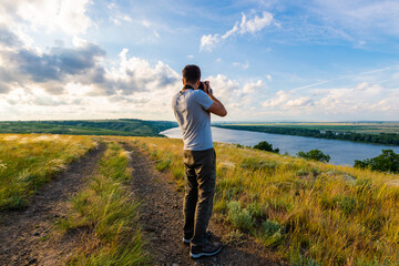 Back view of a photographer taking pictures of river landscape