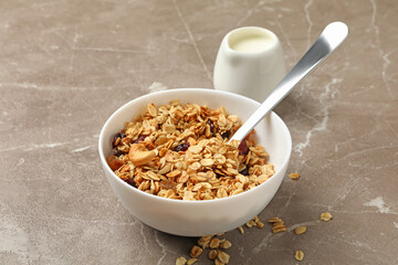 Bowl with granola and milk on gray background