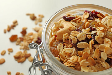 Glass jar with granola on white background, close up