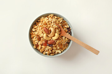 Bowl and spoon with tasty granola on white background