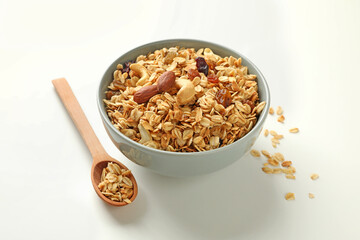 Bowl and spoon with tasty granola on white background