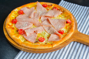 Pizza with bacon, salami and vegetables. Ham and tomatoes pizza with melted cheese.
