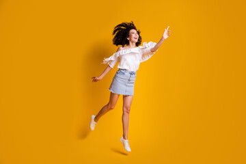 Fototapeta na wymiar Full size photo of cute cheerful brunette woman jumping see something wear top skirt isolated on yellow color background