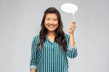 people and communication concept - happy asian young woman holding blank speech bubble over grey background