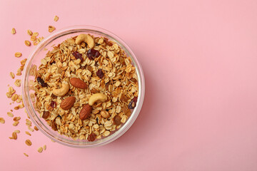 Bowl with tasty granola on pink background