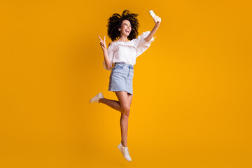 Fototapeta na wymiar Full size profile photo of cute cheerful brunette curly girl jump wear white top skirt sneakers isolated on yellow background