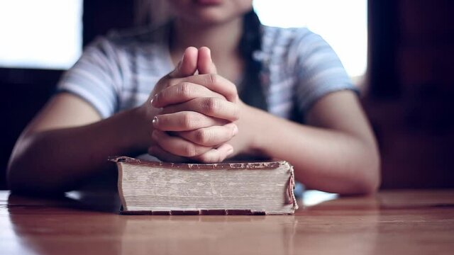 Close up hands of young woman praying on Bible, church in home, Home church during quarantine coronavirus Covid-19, Religion concept.