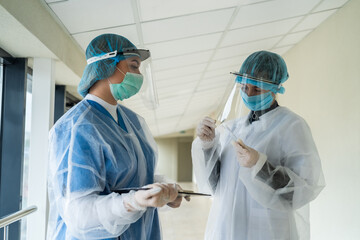 Two female doctors with protective clothes holds test tube with blood sample to coronavirus