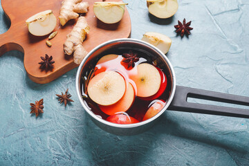 Saucepan with hot mulled wine on color background