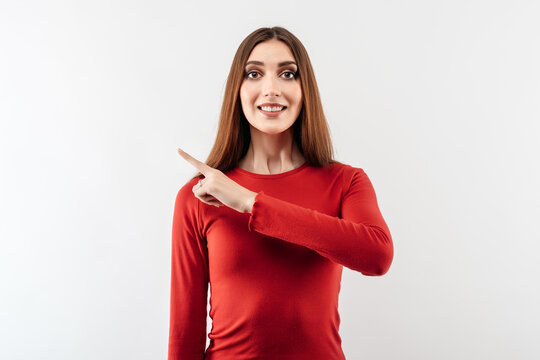 Image of young happy woman pointing forefinger aside, shows place for ad