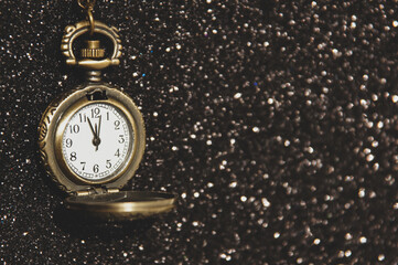 The antique clock shows almost midnight against a sparkling black background. New year concept. Place for your text.