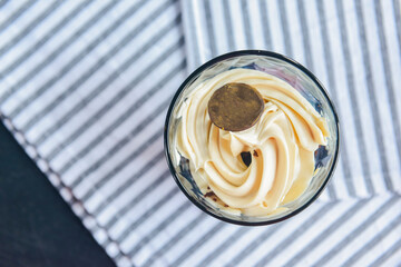Berry and mascarpone trifle dessert with whipped cream served in a glass. Restaurant dessert over blue table cloth.