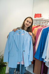 Smiling woman shopper choosing new garments at fashion story