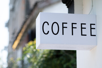 White coffee signage on the wall mockup with green plants on background 