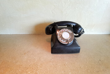 Retro rotary black dial telephone with Chinese and Arabic numerals on the marble table on wall background with copy space.