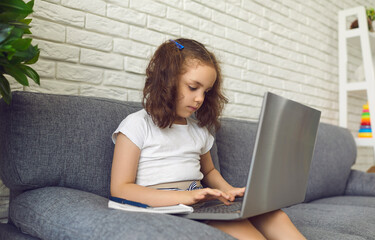 Online child education. Little girl makes video chat lesson laptop at home.