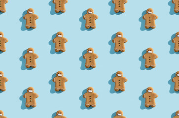 Fototapeta premium Pandemic gingerbread man pattern. Conceptual pastry design. Festive bakery illustration. Decorated icing figure biscuits in protective mask isolated on blue pastel.