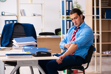 Young male employee doing sport exercises at workplace