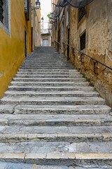 Fototapeta na wymiar narrow stone stairs with railing between stone walls