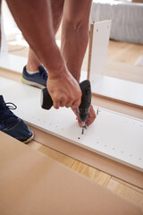 Handyman worker assembling furniture in new apartment, moving in and being hardworking.