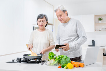 Senior couple looks recipe on cellphone while cook