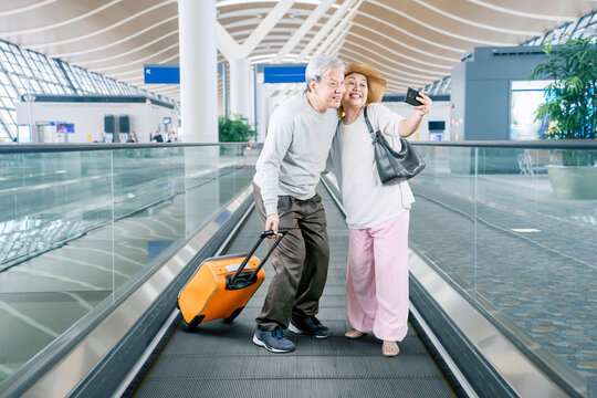 Senior couple take selfie while carry luggage