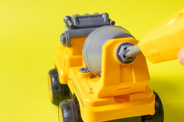 The toy typewriter is a concrete mixer and screwdriver that twists the cog on a yellow background. Photos for a toy store and educational activities. Early development of children.